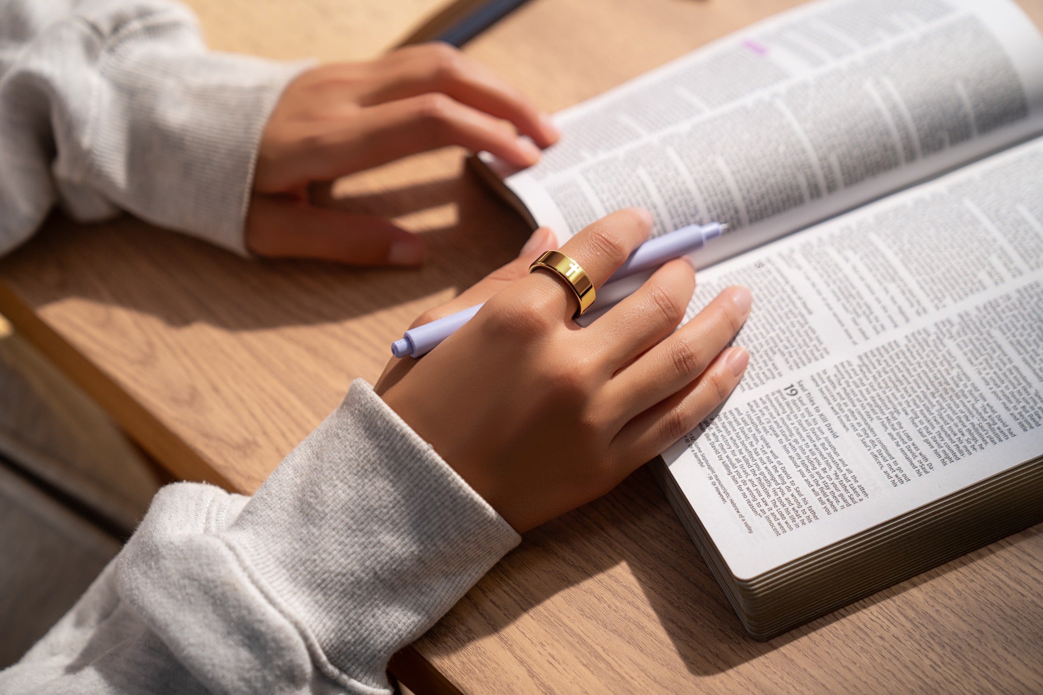 A hand wearing Elah Ring while reading and writing